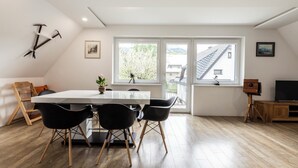 Ein stilvoller Essbereich mit einem weißen Tisch, schwarzen Stühlen und einem Holzboden.