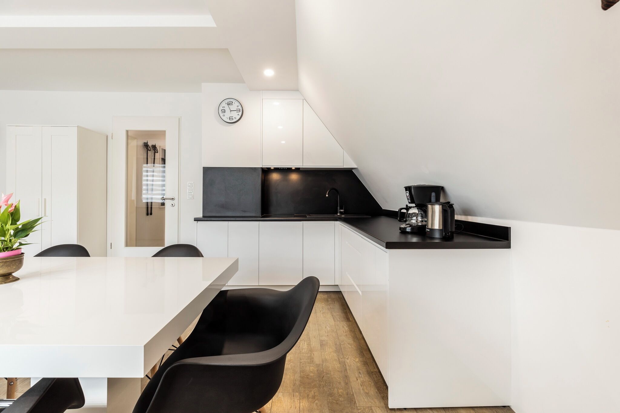 A modern kitchen with white cabinets, a black countertop, and a coffee machine.