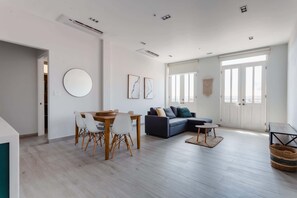 Una sala de estar moderna con comedor, un sofá y un espejo redondo en la pared.