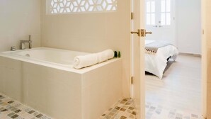 Une salle de bain moderne avec une baignoire sur pieds, un panneau décoratif en treillis et un carrelage à motifs.