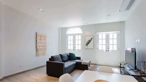A modern living room with a sectional sofa, a dining table, and a large window providing natural light. - w* | Perfect 2BR in Casco Antiguo w/ Balcony (Panamá)
