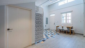 Ein modernes Interieur mit einem Schachbrettfußboden, einem Essbereich mit Stühlen und einer weißen Tür.