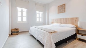 A bedroom with a large bed, a wooden headboard, a bedside table with a lamp, and a woven basket on the floor. - w* | Vivid 1BR w/ Magical lighting in Panama (Panamá)