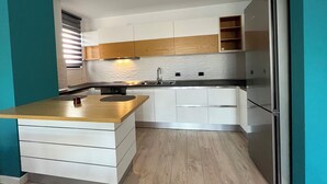 A modern kitchen with white cabinets, a wooden countertop, and a stainless steel refrigerator. - 2 Bedroom Apartment Tirana/ Family friendly (Tirana)