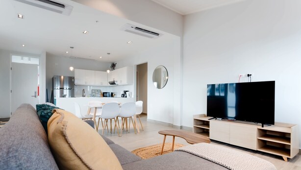 A modern living room with a sofa, a flat-screen TV, and a wooden entertainment unit. - w* | Welcoming 2BR w/ Terrace in Panama (Panamá)