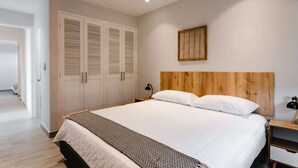 A bedroom with a large bed, wooden headboard, white walls, and a wooden door. - w* | Welcoming 2BR w/ Terrace in Panama (Panamá)