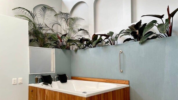 A modern bathroom with a wooden vanity, a large bathtub, and a small wooden bench. - w*| Awesome 2BR w/ 2 Jacuzzis  in El Poblado (Medellín)