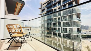 Un appartement moderne doté d'un balcon, d'un fauteuil en osier et offrant une vue sur le paysage urbain.