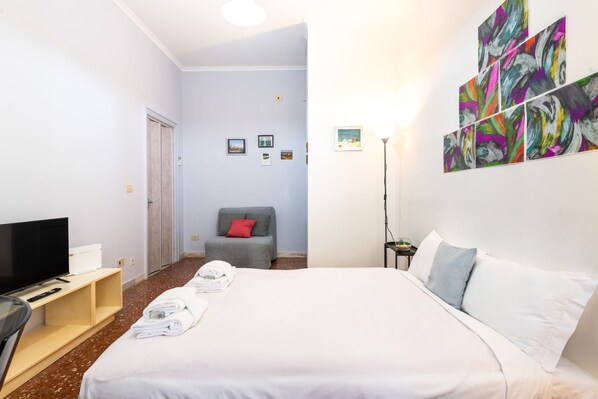 A hotel room with a bed, a TV, a desk, and artwork on the wall. - Magi Apartment in Rome (Rome)