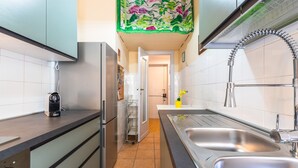 A modern kitchen with stainless steel appliances, a double sink, and a tiled backsplash. - Magi Apartment in Rome (Rome)