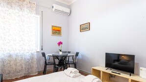 A hotel room with a bed, a TV, a desk with a chair, and a small table with a potted plant. - Magi Apartment in Rome (Rome)