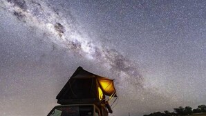 Un vehículo con una estructura grande, abierta y triangular en la parte superior, posiblemente para observación o proyección de luz, bajo un cielo estrellado.