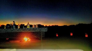 Vista nocturna de un puente con botellas iluminadas y fuego abajo.