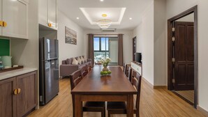 A modern kitchen with a central island, built-in appliances, and a dining area with a wooden table and chairs. - ATP Galaxy Hotel & Apartment Danang (Da Nang)