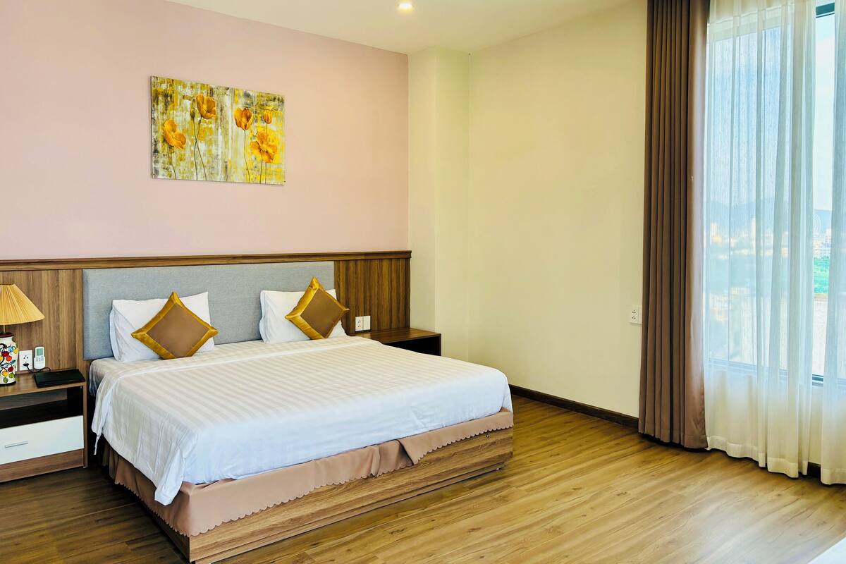 A hotel room with a large bed, a nightstand, a lamp, and a painting on the wall.