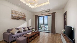 A modern living room with a sofa, coffee table, and a flat-screen TV. - ATP Galaxy Hotel & Apartment Danang (Da Nang)