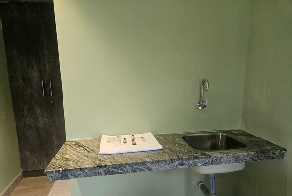 Una cocina con encimera de granito, pileta de acero inoxidable y puerta de madera oscura.