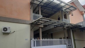 Ein zweigeschossiges Gebäude mit einem überdachten Balkon, einem weißen Tor und einer Klimaanlage an der Wand.