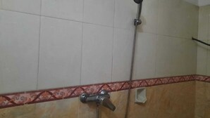 Ein Badezimmer mit Dusche, Fliesen und einer dekorativen Bordüre.