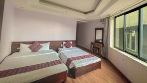 Habitación de hotel con dos camas, un escritorio pequeño, un espejo y un ventanal grande.