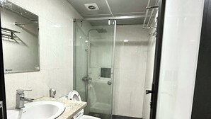 Un baño moderno con cabina de ducha de vidrio, un lavamanos y un inodoro.