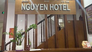 Un letrero de hotel con la leyenda 'NGUYEN HOTEL' y los nombres de ciudades 'LONDON' y 'NEW YORK', indicando ubicaciones internacionales.