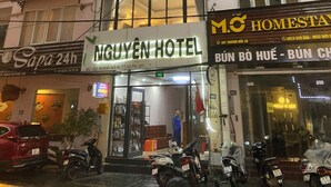 Un edificio de varios pisos con un cartel llamativo que dice NGUYEN HOTEL.