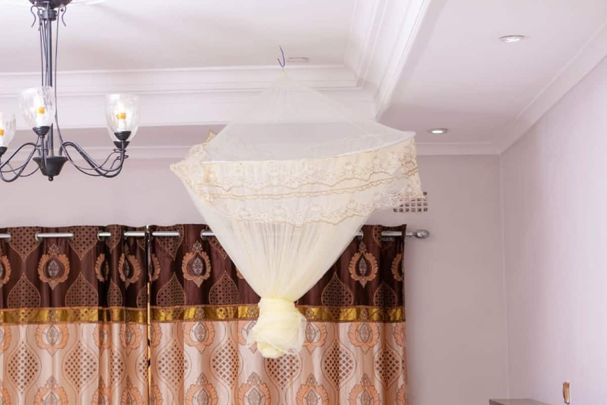 Quarto com cama, mesa de cabeceira, guarda-roupa, candelabro e cortinas.