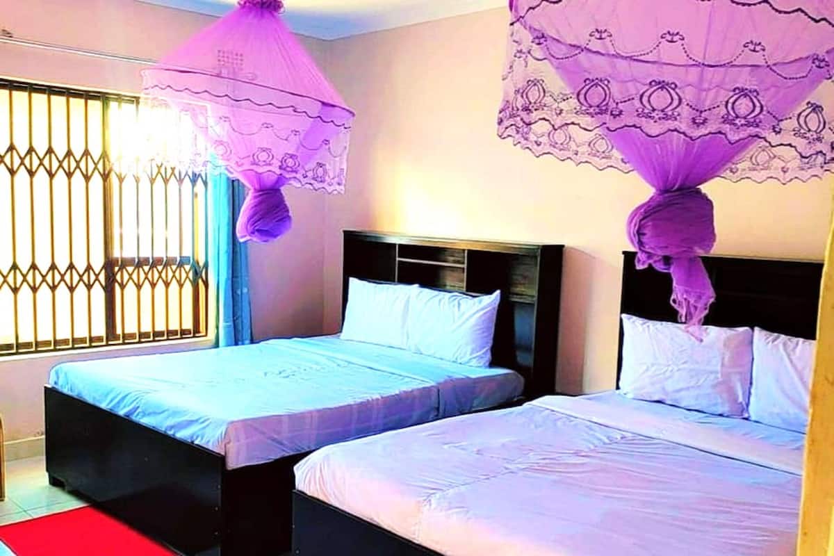 Quarto com duas camas, cada uma com cabeceira e dossel.