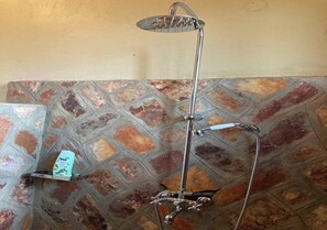 Une douche équipée d’un pommeau de douche à main et d’un flexible également à main.