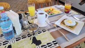 A breakfast table with a cup of coffee, a plate of eggs, and a bottle of water. - Stevalyn's Ridge View Lodge (Jinja)