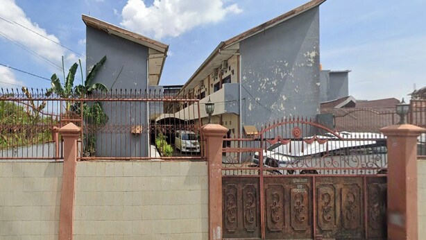 A gated residential area with a two-story building, a tiled wall, and a metal gate. - Hotel O Kost Stan (Negeri Lama)