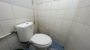 A small, basic bathroom with a toilet, a visible pipe, and a tiled floor. - Hotel O Kost Stan (Negeri Lama)