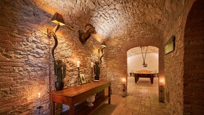 A rustic stone-walled room with a wooden bench, cacti, candles, and wall-mounted lamps. - Villa Camelia by Elite Villas (Colle di Val d'Elsa)