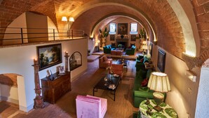 A spacious loft with a high arched brick ceiling, a fireplace, and a cozy seating area with sofas and a coffee table. - Villa Camelia by Elite Villas (Colle di Val d'Elsa)