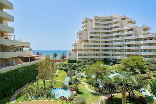 A hotel with multiple balconies, a swimming pool, and a view of the sea.