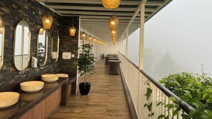 A corridor with a wooden floor, a row of round mirrors, and hanging lamps. - British County Resort (Devikolam)