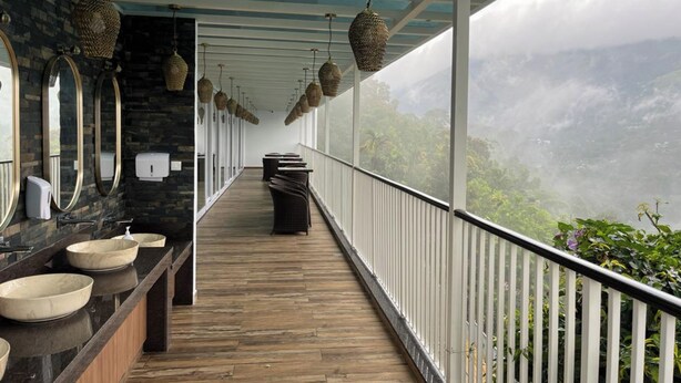 A long corridor with a wooden floor, a row of sinks, and hanging woven light fixtures. - British County Resort (Devikolam)