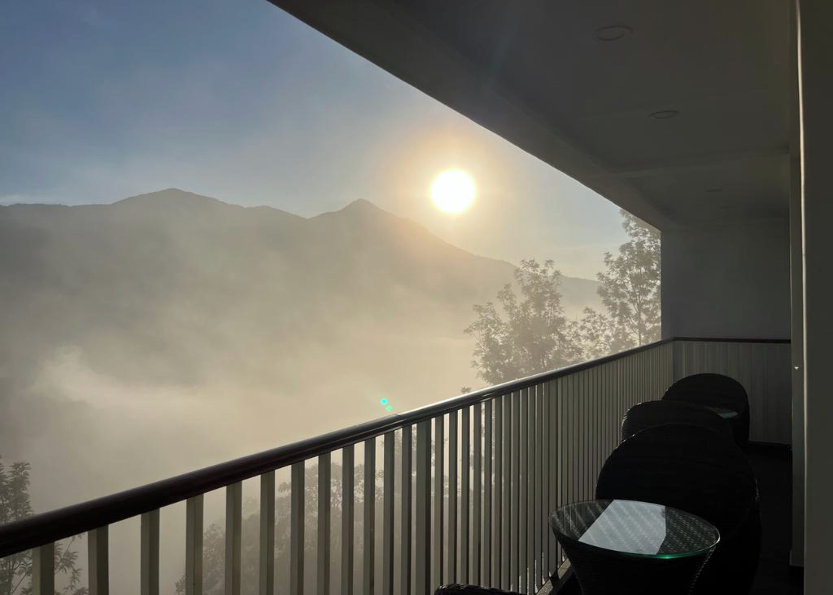 Ein Balkon mit Blick auf Berge und Sonne.