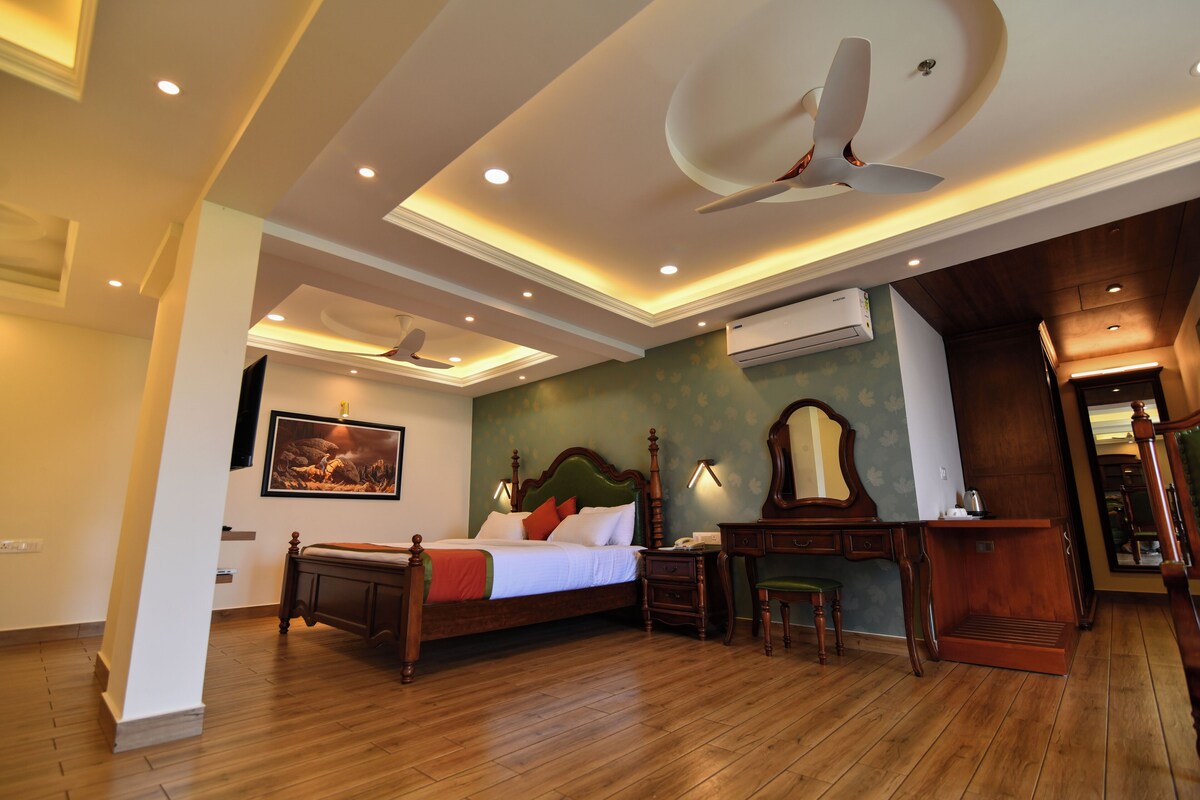 A hotel room with a wooden bed, a desk, a chair, a ceiling fan, and recessed lighting.
