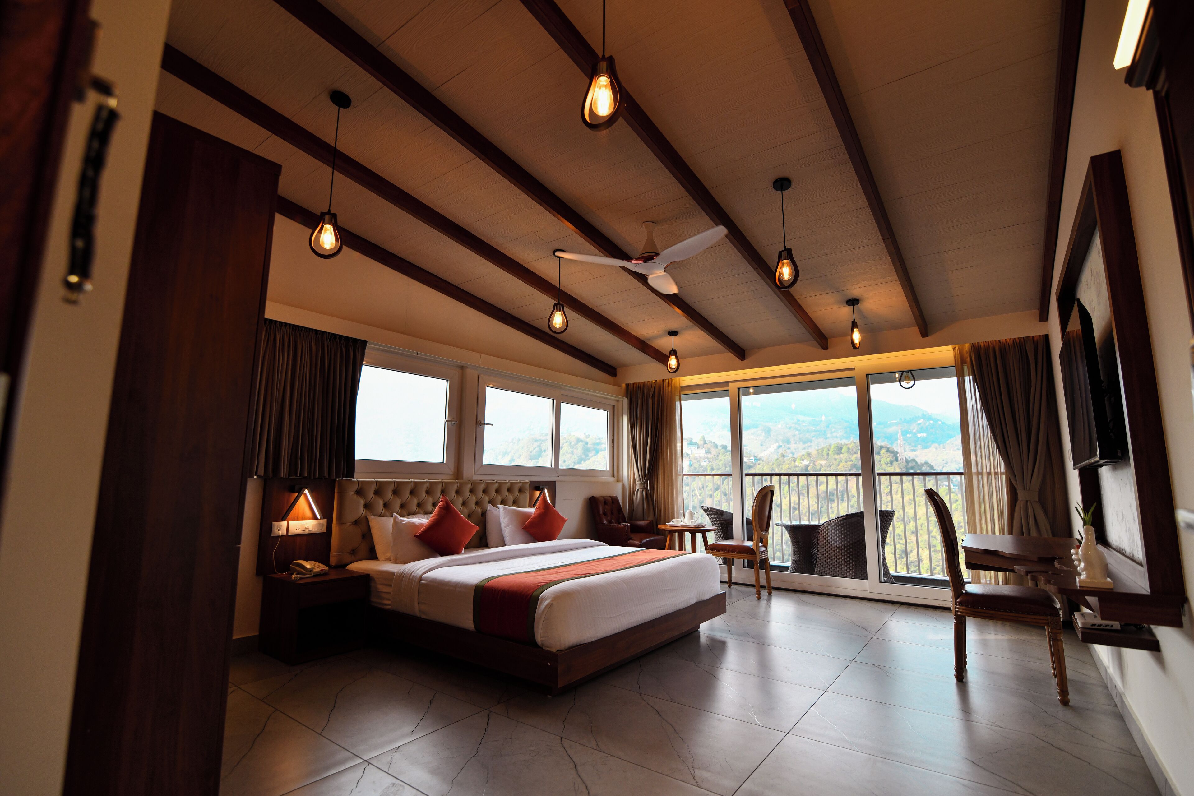 A hotel room with a large bed, a ceiling fan, and a view of the outdoors.