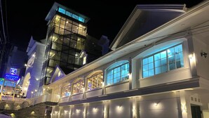 A multi-story building with illuminated windows and a prominent tower section. - British County Resort (Devikolam)
