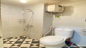 Ein Badezimmer mit schwarz-weiß kariertem Boden, einer Dusche, einer Toilette und einem an der Wand befestigten Händetrockner.