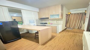 Eine kleine Küche mit Holzausbau, einer Arbeitsplatte, einem Kühlschrank und einem Wasserspender.