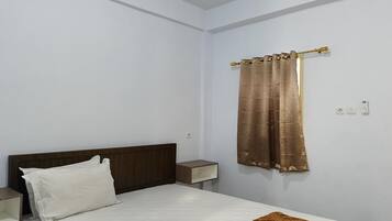 A bedroom with a bed, a nightstand, a wall-mounted shelf, and a curtain.