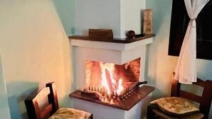 Un ambiente accogliente con camino, due poltrone in legno, un tavolino e una finestra con tende.