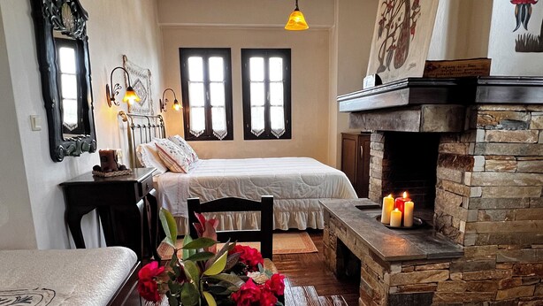 Un ambiente accogliente con un letto, un tavolo con un vassoio di tazze da tè, un vaso di fiori e un camino.