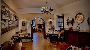 Un'ampia stanza con pavimento in legno, un lampadario, un tavolo da pranzo con sedie e una libreria piena di libri.