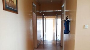 A corridor with tiled floors, a framed picture on the wall, and a blue object hanging on the right.