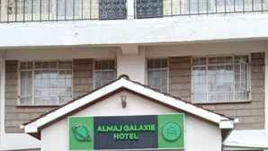 The exterior of the Almaj Galaxie Hotel with a signboard, entrance, and potted plants.
